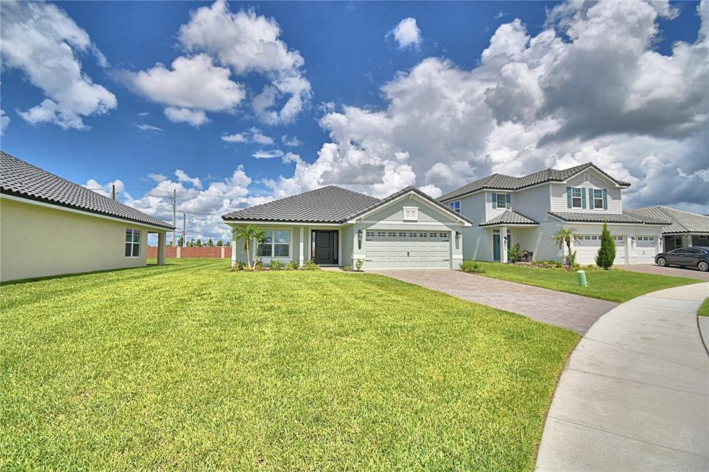 A red front door with a sidelight sits on a covered porch with stone pavers — 4718 GRANDVIEW GLEN DRIVE, AUBURNDALE, FL