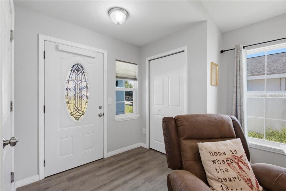 An entryway features light gray walls, wood-look flooring, a white front door, and a recliner — 14584 20TH ST, DADE CITY, FL