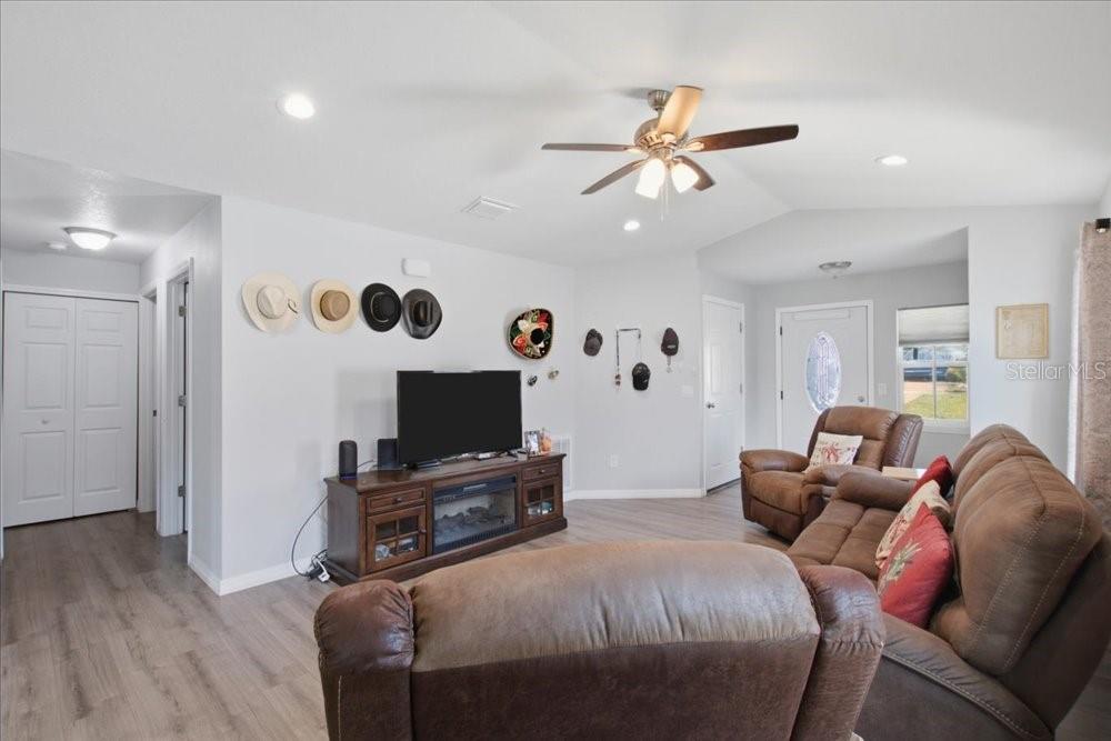 A living room features light wood-look flooring, a ceiling fan, and a brown leather sofa — 14584 20TH ST, DADE CITY, FL