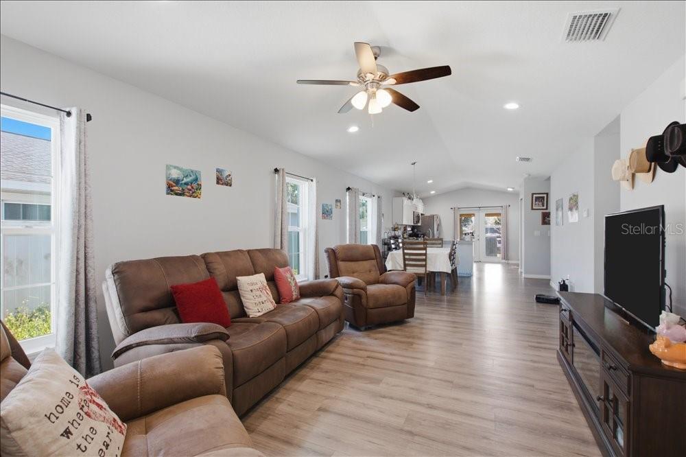 A living room with wood-look flooring, a brown sofa, a recliner, and a ceiling fan — 14584 20TH ST, DADE CITY, FL
