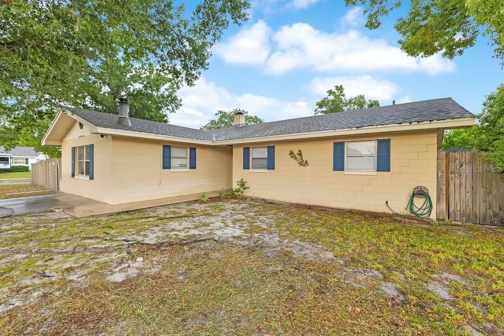 A single-story house with tan block siding, a dark shingled roof, and blue window shutters — 506 CLAYTON CIRCLE, WINTER HAVEN, FL