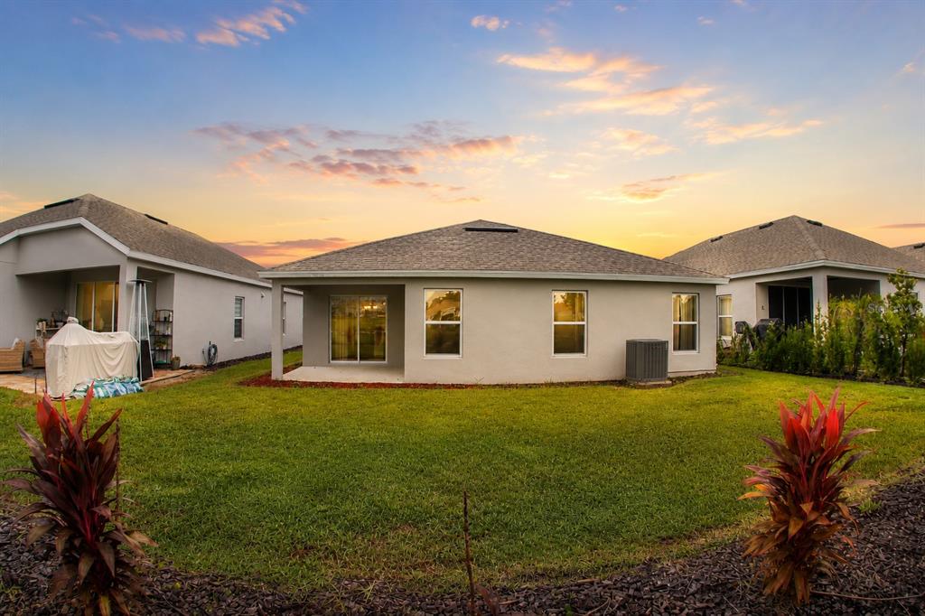 The rear exterior of a single-story house with a lawn, patio, and sunset sky — 2025 HAVASU FALLS AVENUE, DELAND, FL