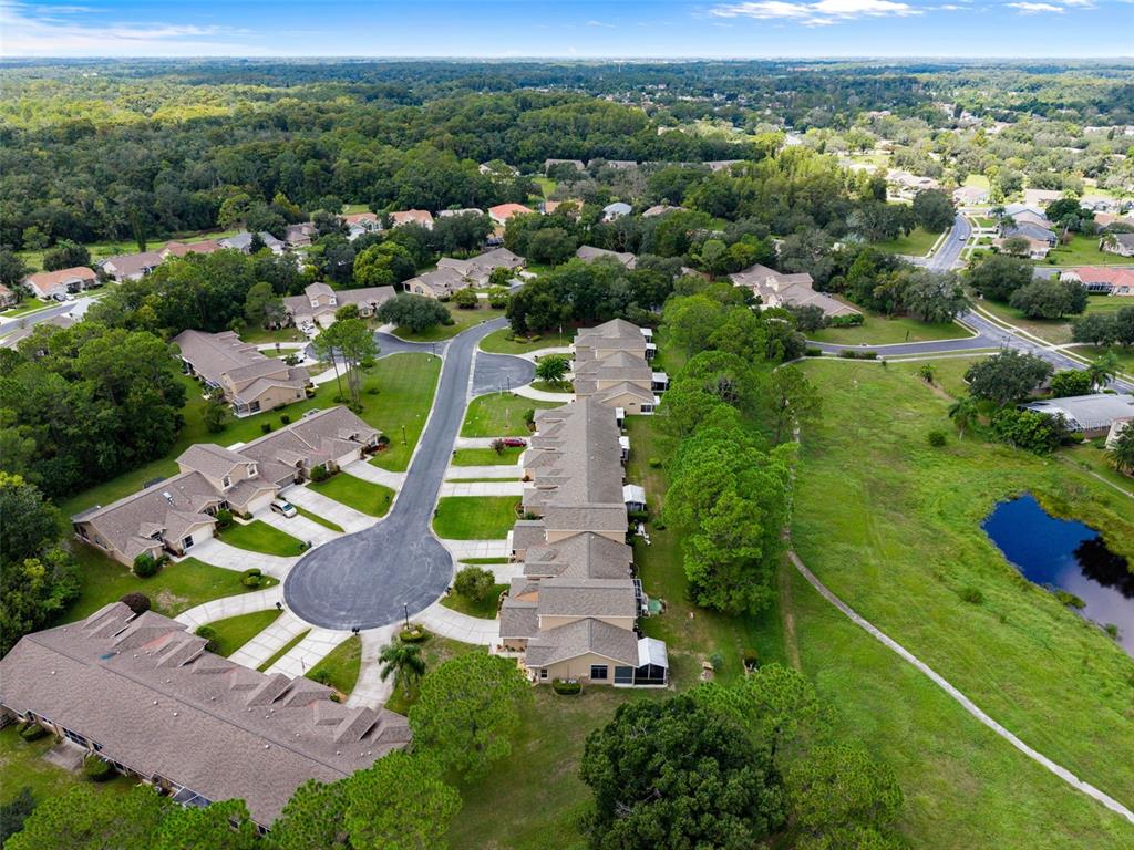 An aerial view shows a residential neighborhood with townhouses, a cul-de-sac, and a small pond — 7414 MOORGATE COURT, NEW PORT RICHEY, FL