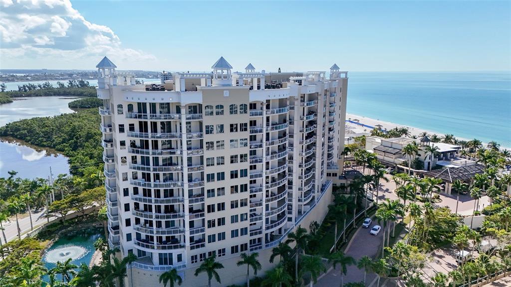 A multi-story residential building with balconies and a covered entrance driveway surrounded by palm trees — 1300 BENJAMIN FRANKLIN DRIVE UNIT 809, SARASOTA, FL