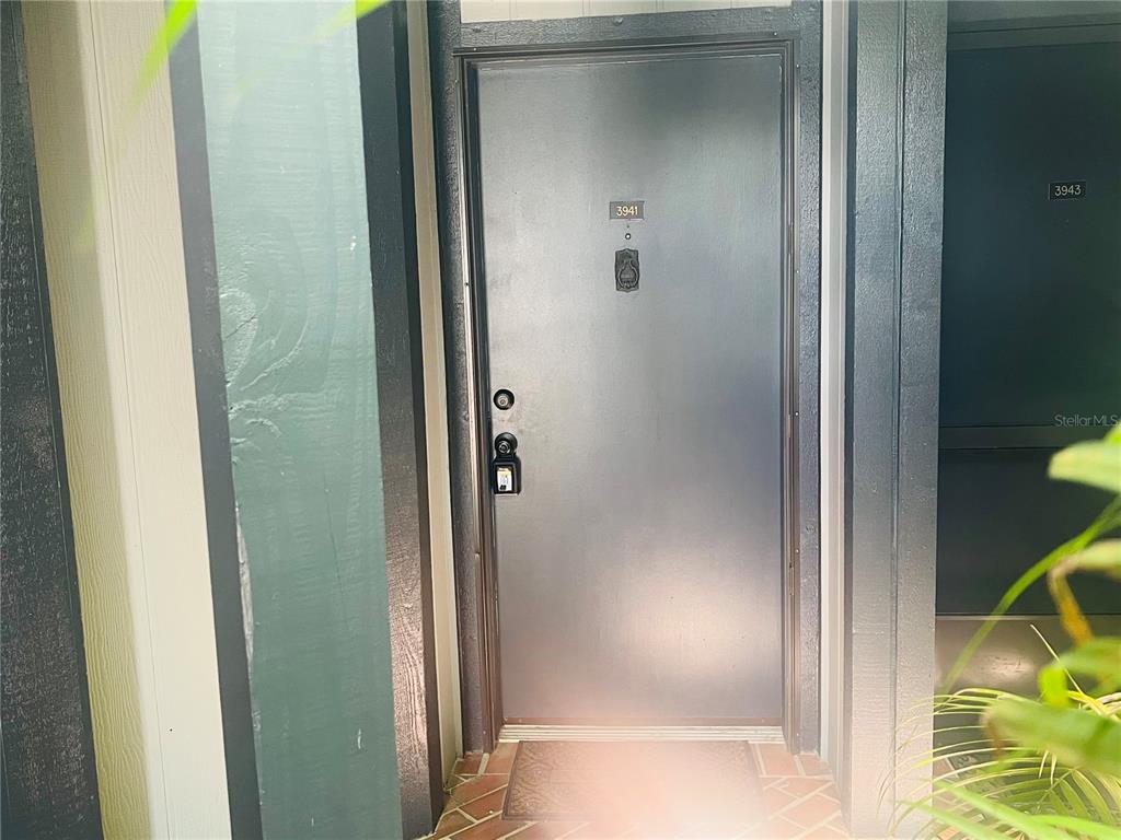 A ground-level patio entrance features a glass door, screened walls, and a stone walkway — 3941 ATRIUM DRIVE UNIT L3, ORLANDO, FL