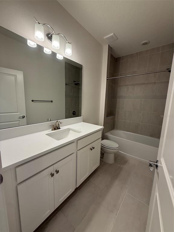 A bathroom features a white vanity, a large mirror, and a tiled shower-tub combination — 5127 BUTTONSAGE DRIVE, ST CLOUD, FL