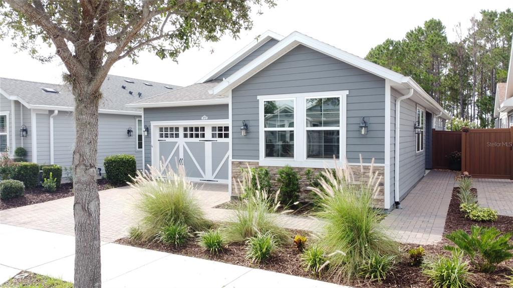 A single-story house with gray horizontal siding, a stone base, and a paved driveway — 372 ALCOVE DRIVE, GROVELAND, FL
