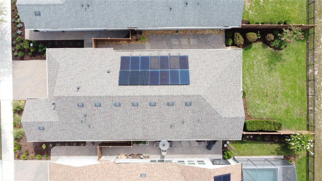 An aerial view shows a house roof with solar panels and a backyard with landscaping — 372 ALCOVE DRIVE, GROVELAND, FL