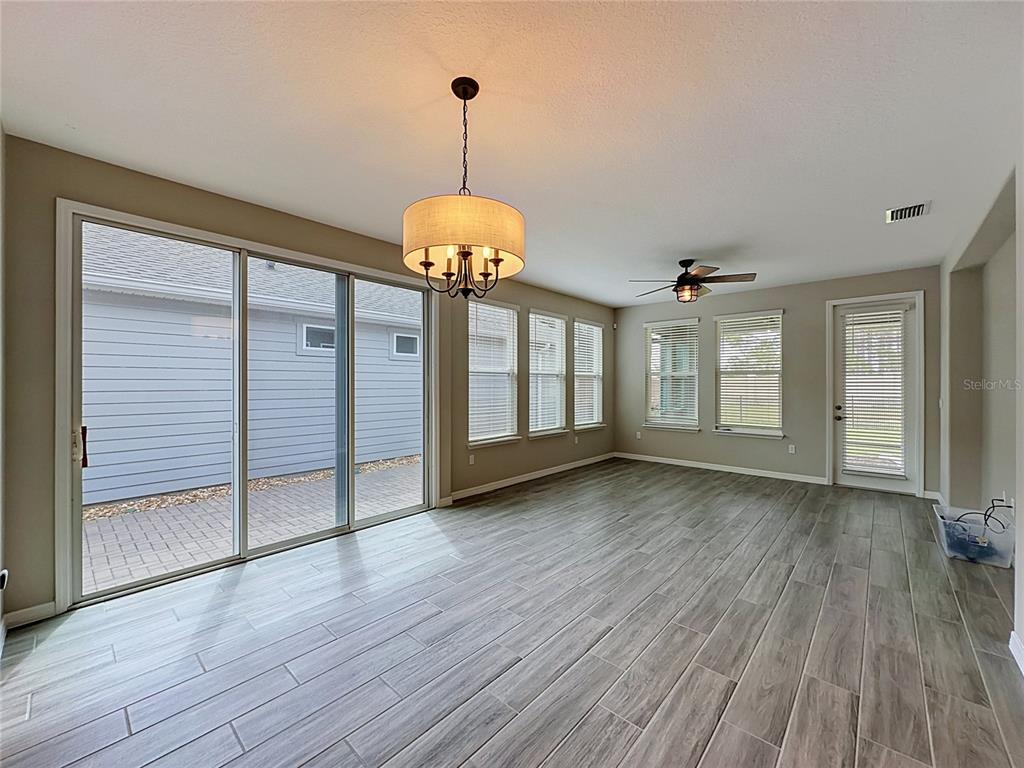 A dining area with wood-look tile flooring, a drum chandelier, and sliding glass patio doors — 372 ALCOVE DRIVE, GROVELAND, FL