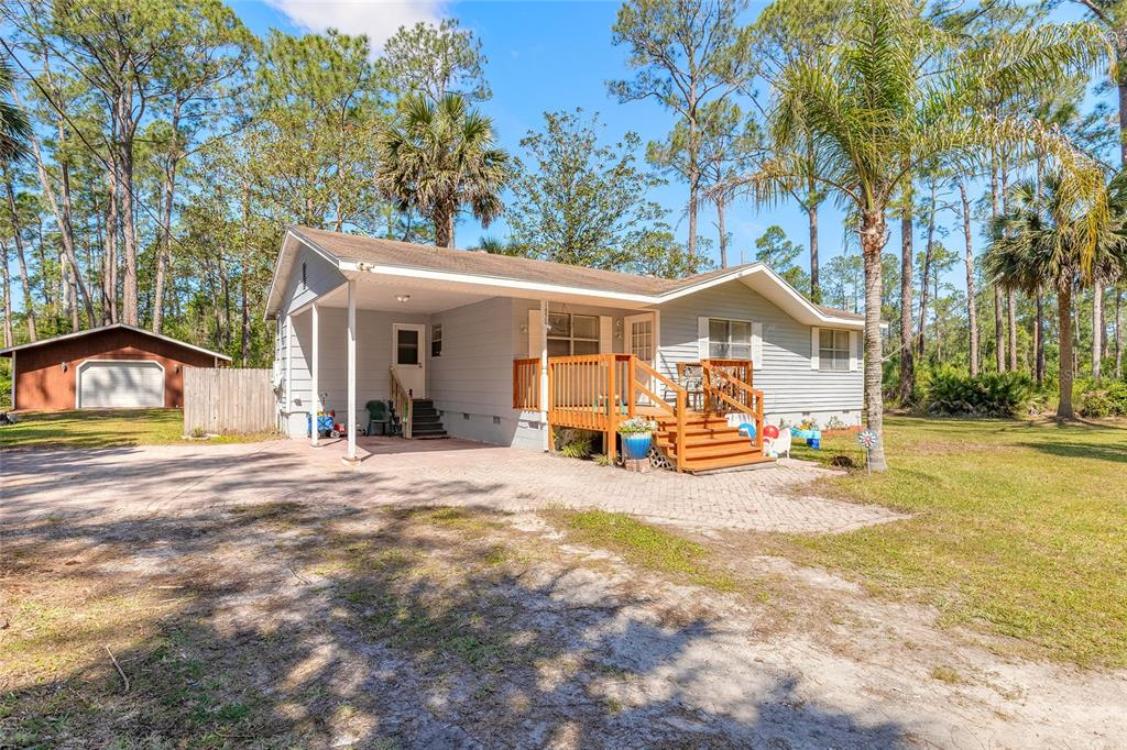 A light-colored house with a wooden bridge in the front yard and palm trees — 1650 11TH AVENUE, DELAND, FL