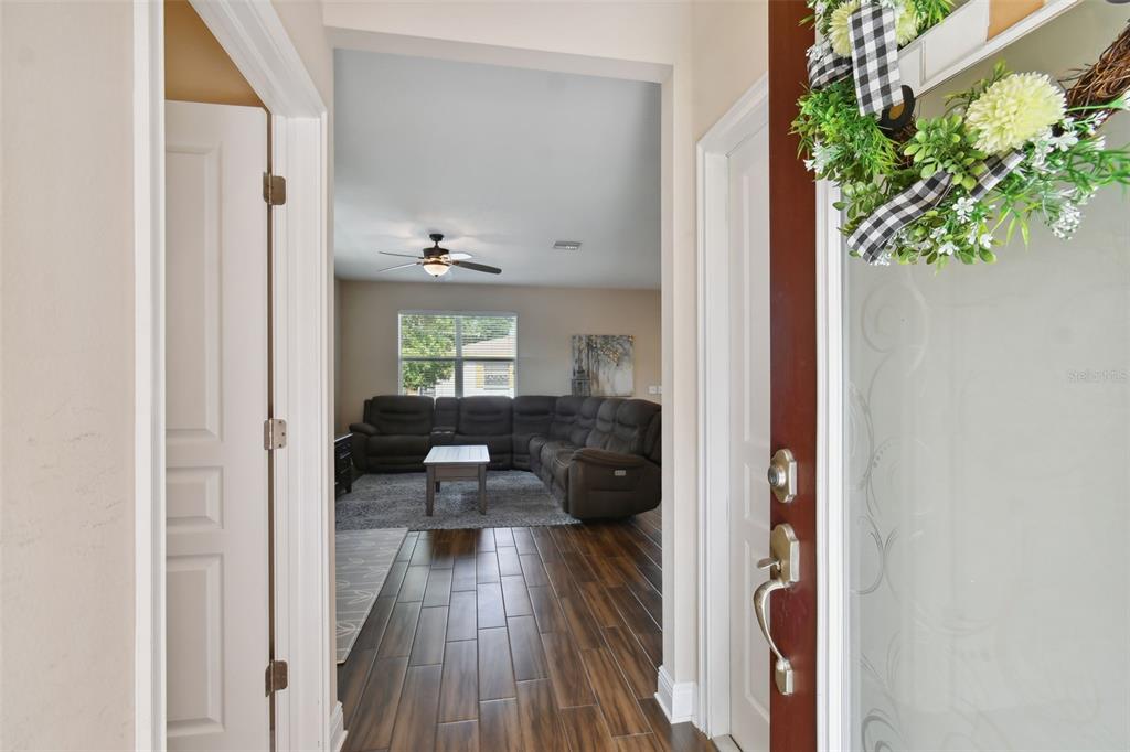An entryway with wood-look tile flooring leads into a living room with a sectional sofa — 7111 S WEST SHORE BOULEVARD, TAMPA, FL