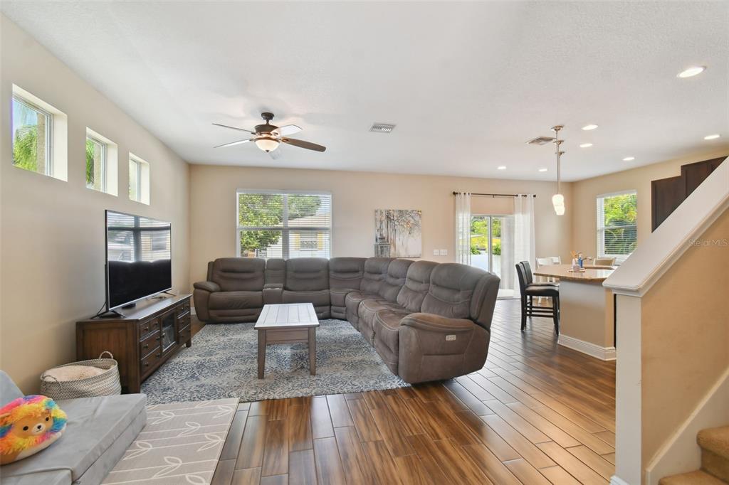 A living room with a large sectional sofa, wood-look tile floors, and an open kitchen — 7111 S WEST SHORE BOULEVARD, TAMPA, FL