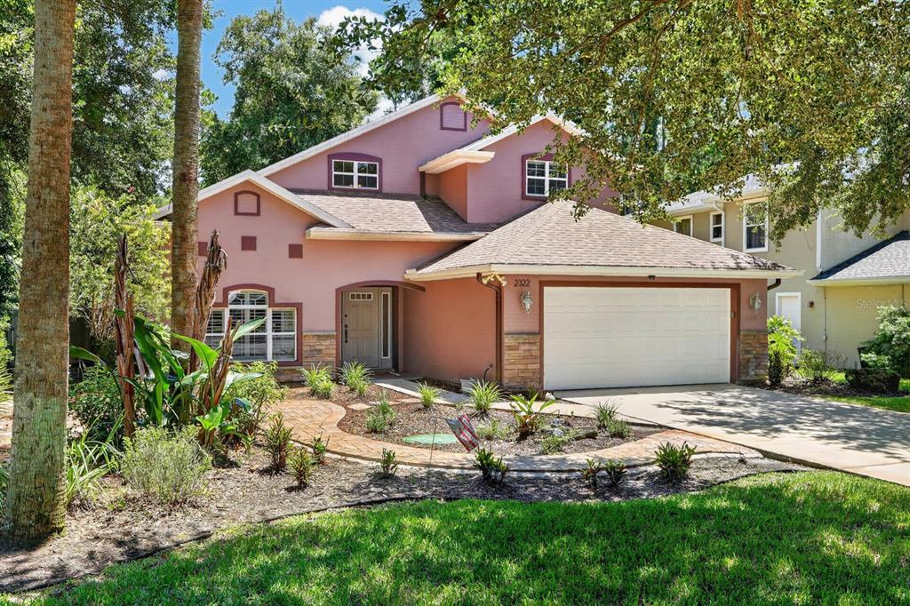 A two-story house with a pink stucco exterior, a two-car garage, and a landscaped yard — 2322 STONEBRIDGE WAY, FLAGLER BEACH, FL