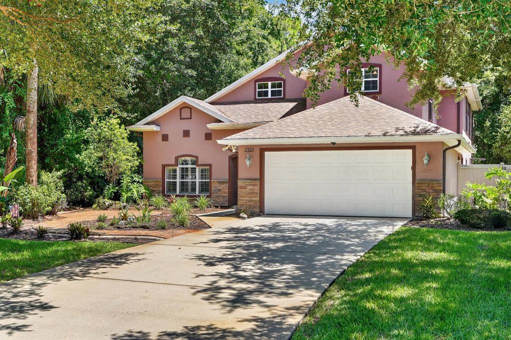 A two-story house with a tan stucco exterior, stone accents, and a two-car garage — 2322 STONEBRIDGE WAY, FLAGLER BEACH, FL