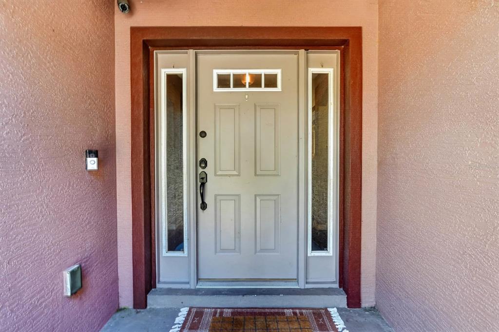 A light gray front door with side windows and a small top window under a porch — 2322 STONEBRIDGE WAY, FLAGLER BEACH, FL