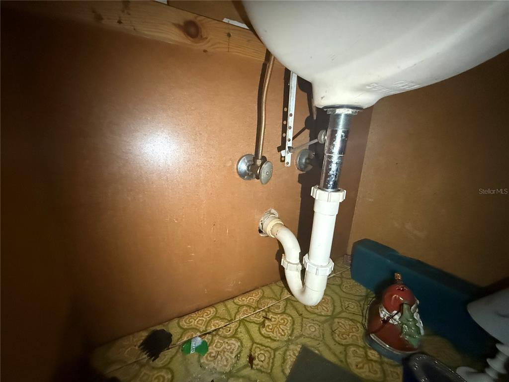This image shows the plumbing pipes and drain assembly beneath a bathroom sink — 10616 GODFREY LANE, ORLANDO, FL