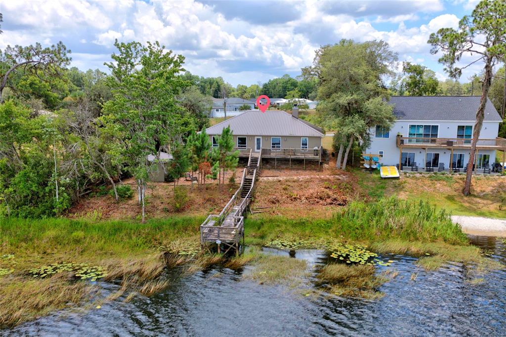 An aerial view shows a tan house with a metal roof, deck, and private wooden dock — 13059 NE 7TH LOOP, SILVER SPRINGS, FL