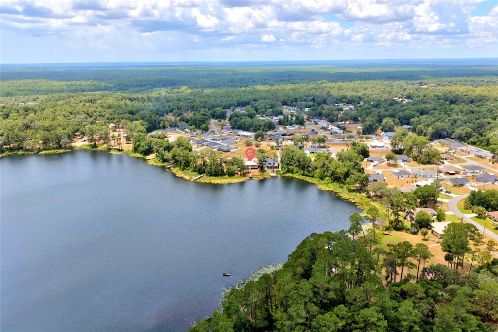 An aerial view shows a house with a red location pin beside a lake — 13059 NE 7TH LOOP, SILVER SPRINGS, FL
