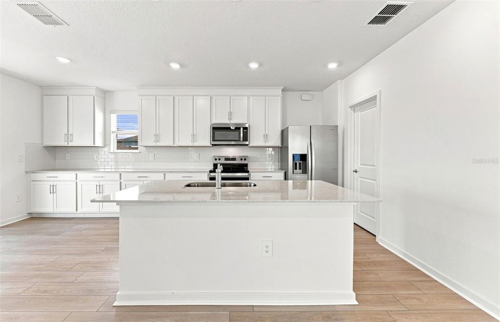 A mudroom entryway features a black storage bench, a round mirror, and a white door — 1436 HAMILTON WAY, LAKE ALFRED, FL