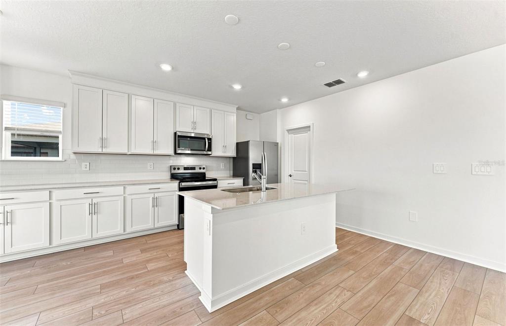 A kitchen with a white island, stainless steel appliances, and a dining area with views — 1436 HAMILTON WAY, LAKE ALFRED, FL