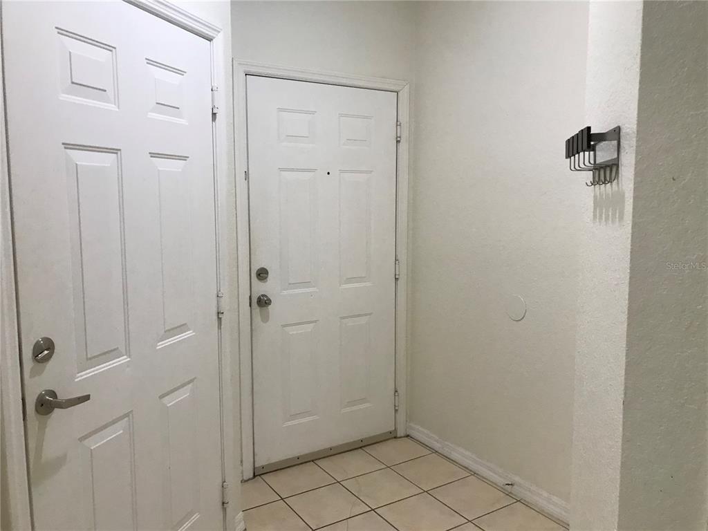 An entryway features white doors, tiled flooring, and a wall-mounted coat rack — 2490 LANCIEN COURT UNIT 4, ORLANDO, FL