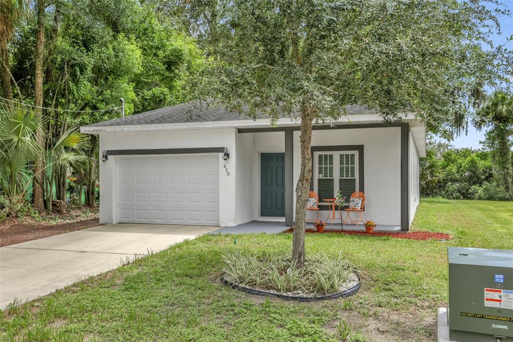 A single-story white house with a garage, a dark front door, and a front yard — 430 W WALTS AVENUE, DELAND, FL