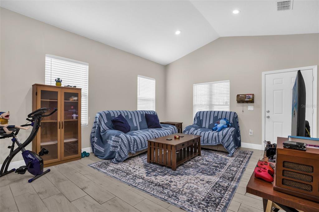 A living room features a blue patterned rug, two sofas with blue throws, and light flooring — 430 W WALTS AVENUE, DELAND, FL