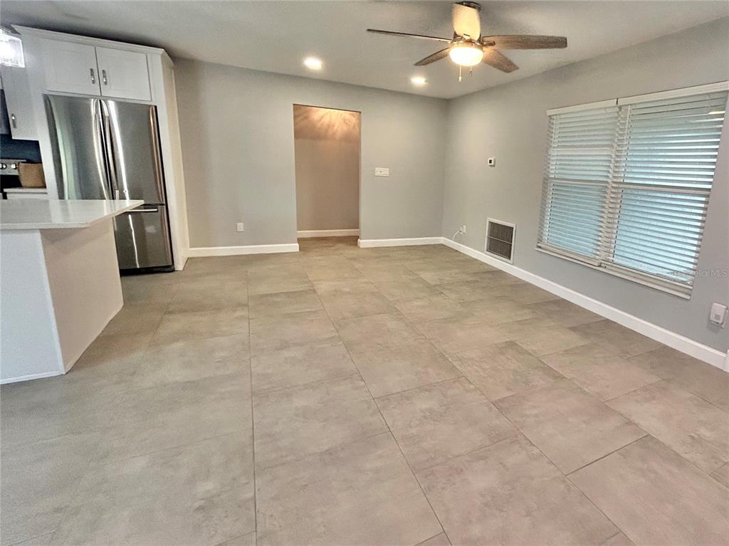 A modern kitchen features white cabinets, stainless steel appliances, a center island, and wood-look flooring — 1444 OVERCASH DRIVE, DUNEDIN, FL