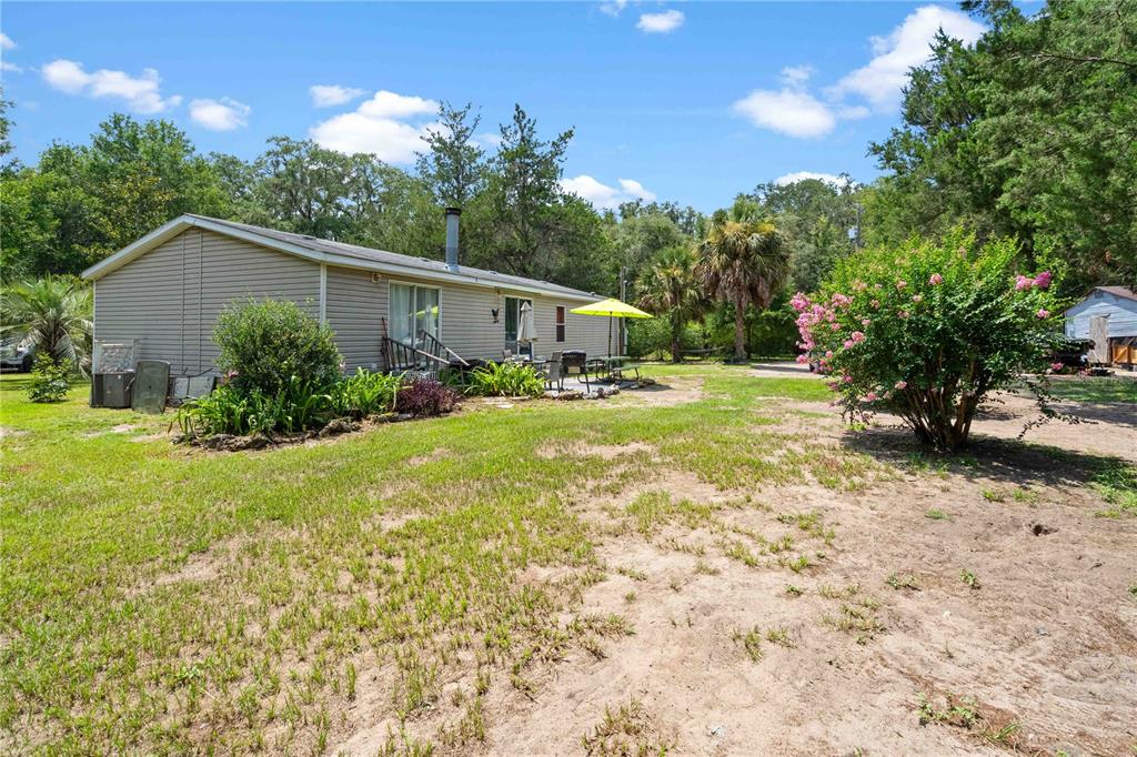 A living room with wood-look flooring, a brick fireplace, and an adjacent dining area — 151 NE 164TH AVENUE, WILLISTON, FL