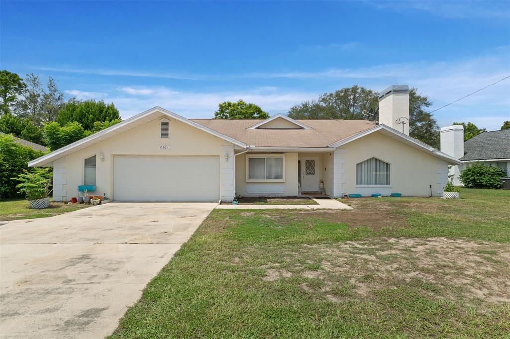 A single-story house with a beige exterior, a two-car garage, and a large chimney — 2501 MARINER BOULEVARD, SPRING HILL, FL