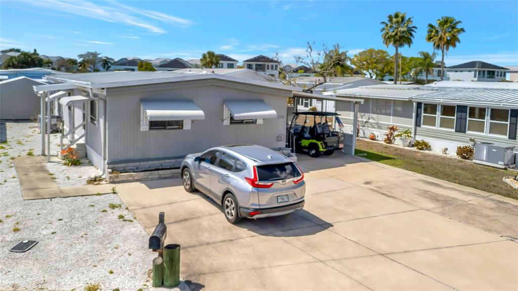 A light gray manufactured home features a concrete driveway, a silver SUV, and a golf cart — 110 E SAINT LUCIA LOOP, APOLLO BEACH, FL