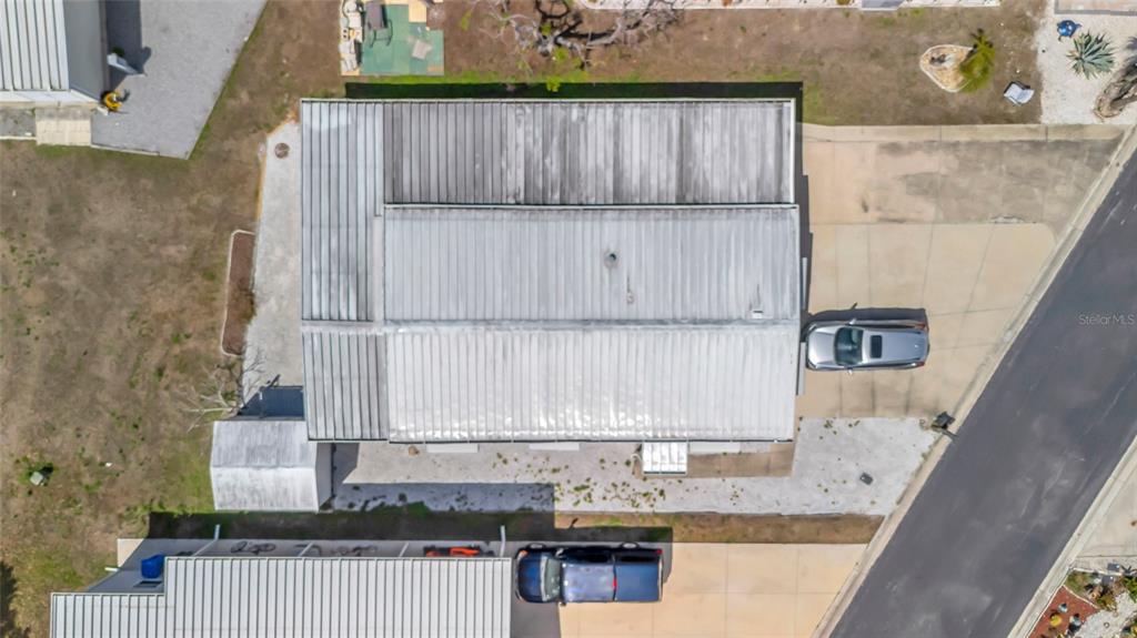 An aerial view shows a house with a metal roof, a driveway, and two parked cars — 110 E SAINT LUCIA LOOP, APOLLO BEACH, FL