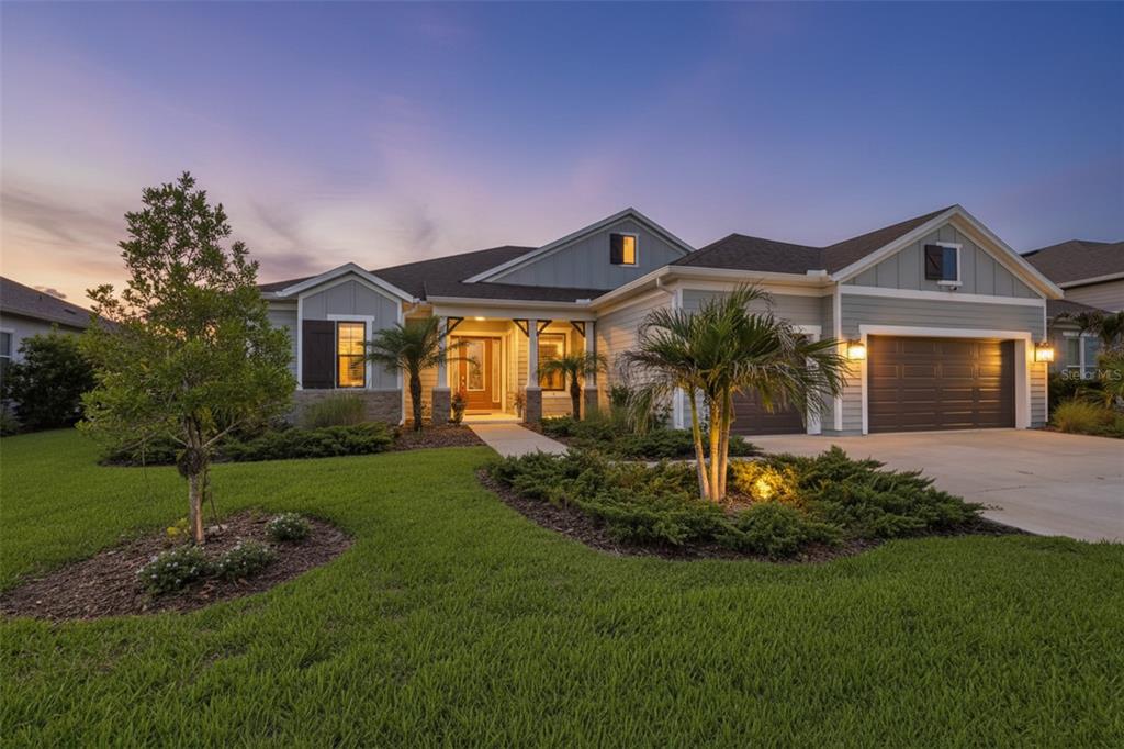 A single-story house with light gray siding, a dark garage, and a landscaped front yard — 14269 SKIPPING STONE LOOP, PARRISH, FL