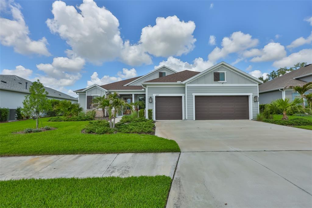 A single-story house with light gray siding, a three-car garage, and a landscaped front yard — 14269 SKIPPING STONE LOOP, PARRISH, FL