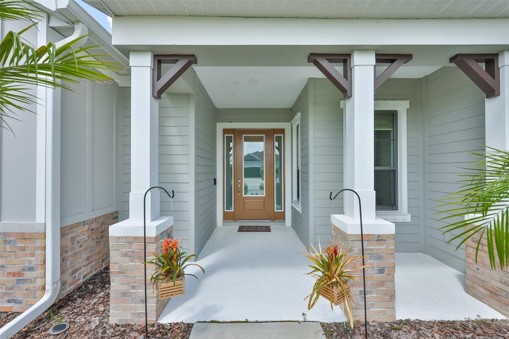 The exterior entrance features a covered porch with brick pillars, white columns, and a wood door — 14269 SKIPPING STONE LOOP, PARRISH, FL