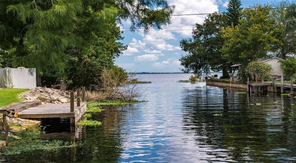 A wooden dock sits on a canal leading to a large lake surrounded by trees — 21722 73RD LANE, VERO BEACH, FL