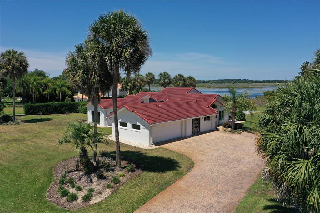 A concrete pool deck features lounge chairs overlooking an infinity pool and a grassy landscape — 13300 SKIING PARADISE BOULEVARD, CLERMONT, FL