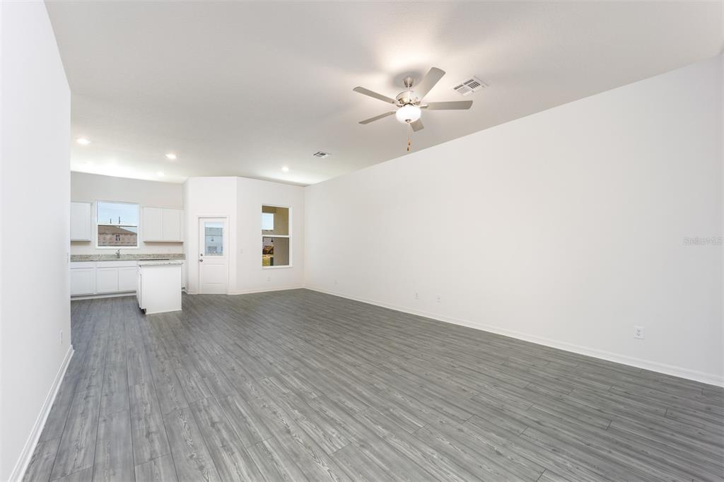 An open-concept living area features gray wood-look flooring, white walls, and a ceiling fan — 654 POPPY LANE, DUNDEE, FL