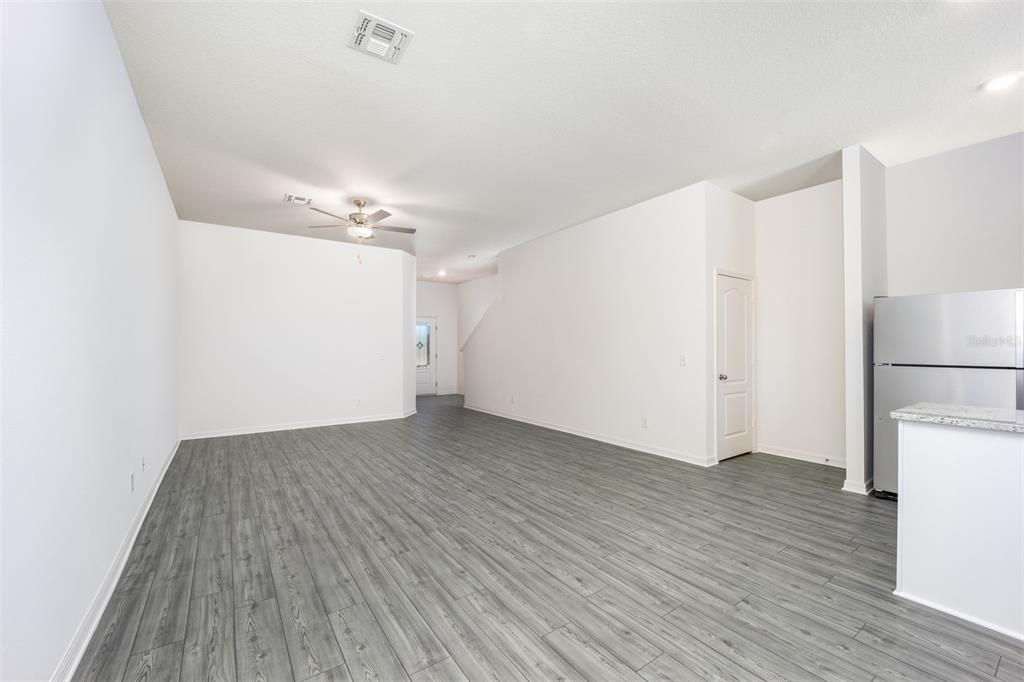 An open-concept living area features gray wood-look flooring, white walls, and a ceiling fan — 654 POPPY LANE, DUNDEE, FL