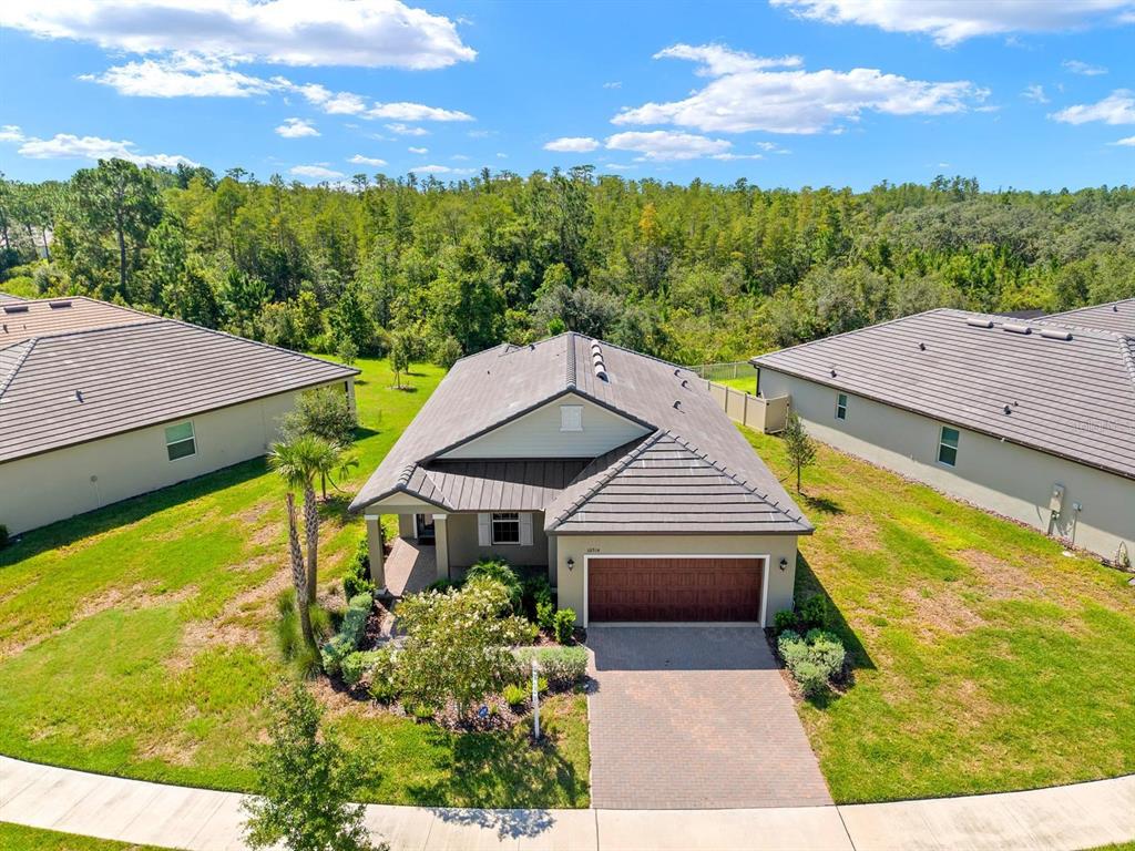An aerial view of a single-story house with a tiled roof and a paved driveway — 10314 BANYAN BREEZE BOULEVARD, LAND O LAKES, FL