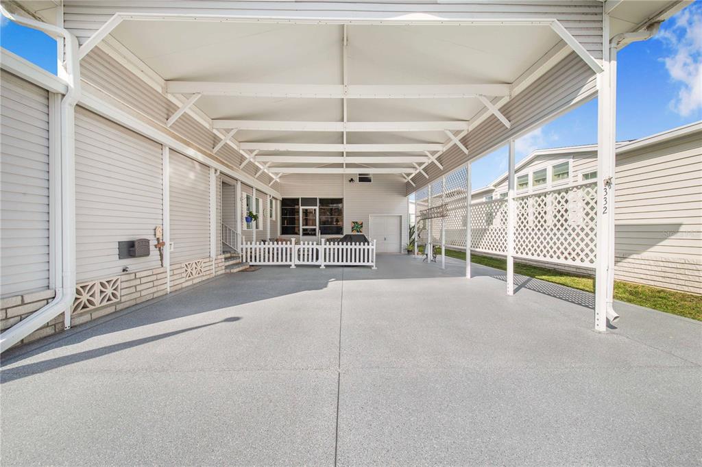 A covered concrete carport features a white picket fence and lattice privacy screen — 332 FAIRWAY BOULEVARD, FROSTPROOF, FL
