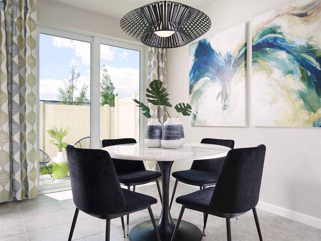 A dining area features a round marble table, four black chairs, and abstract wall art — 16258 BIRD OF PARADISE AVENUE, CLERMONT, FL