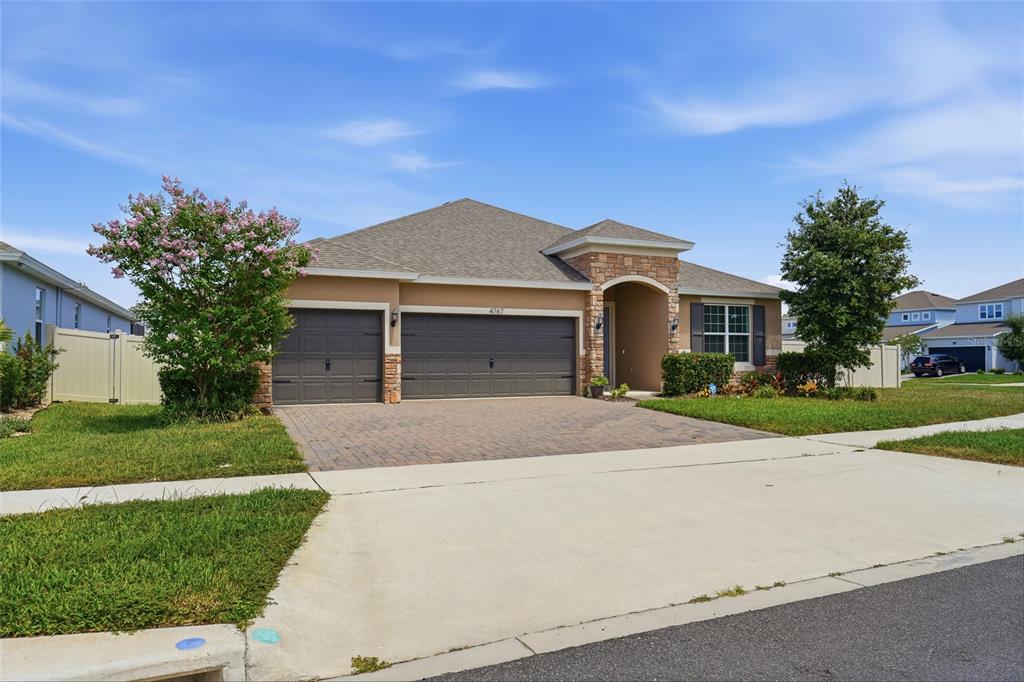 A single-story suburban house with a stone-accented entryway and a three-car garage — 4767 CRAGMERE LOOP, CLERMONT, FL