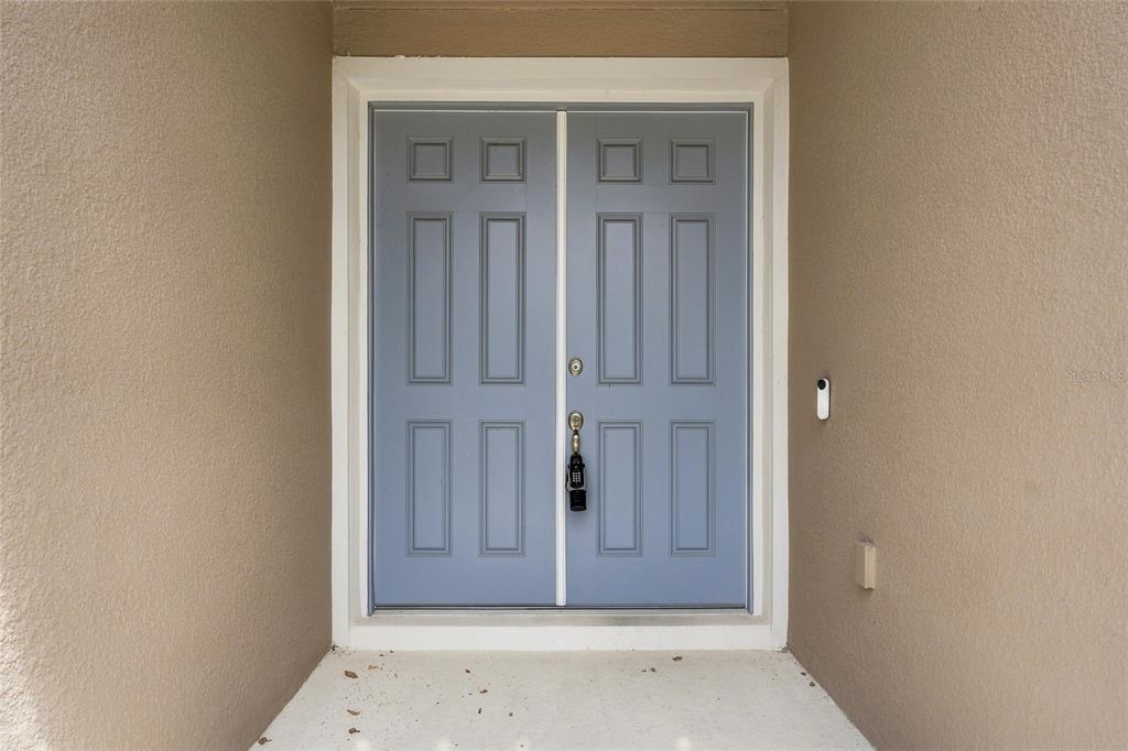 A light blue double front door with a digital lock is set in a beige entryway — 4767 CRAGMERE LOOP, CLERMONT, FL