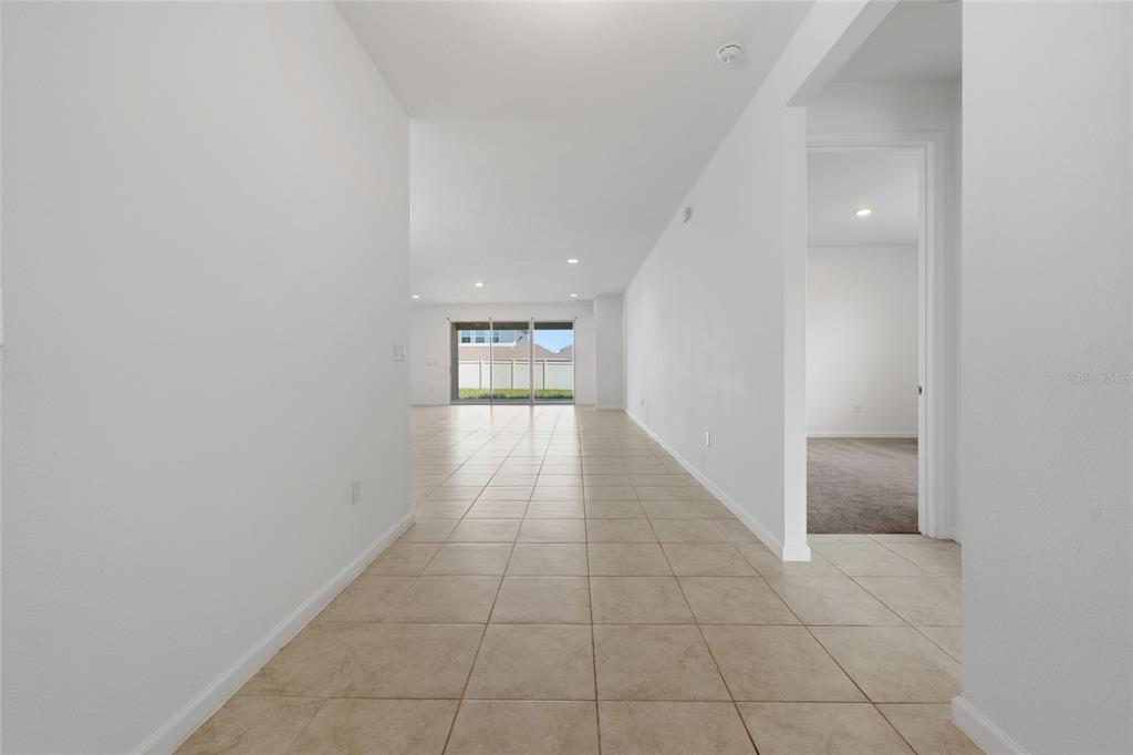 A tiled hallway leads to an open living area with sliding glass doors to the backyard — 4767 CRAGMERE LOOP, CLERMONT, FL