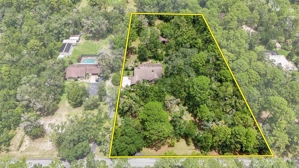 An aerial view shows a house situated on a large, wooded lot with yellow boundary lines — 2705 W LIVE OAK STREET, LECANTO, FL