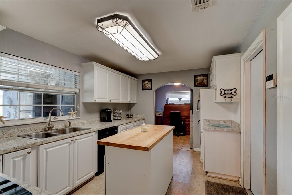 A kitchen with white cabinets, a wooden island, and a sink beneath a window — 1026 LAKE AVENUE, EDGEWATER, FL