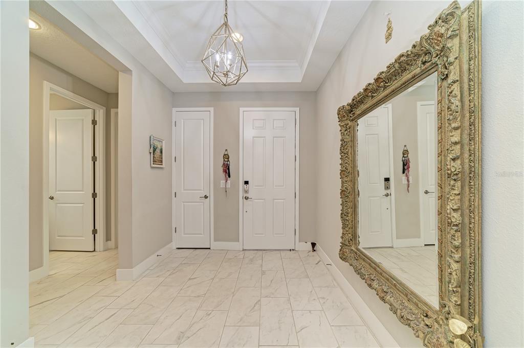 A bright entryway features white tile floors, a tray ceiling with a pendant light, and a mirror — 5440 HOPE SOUND CIRCLE, SARASOTA, FL