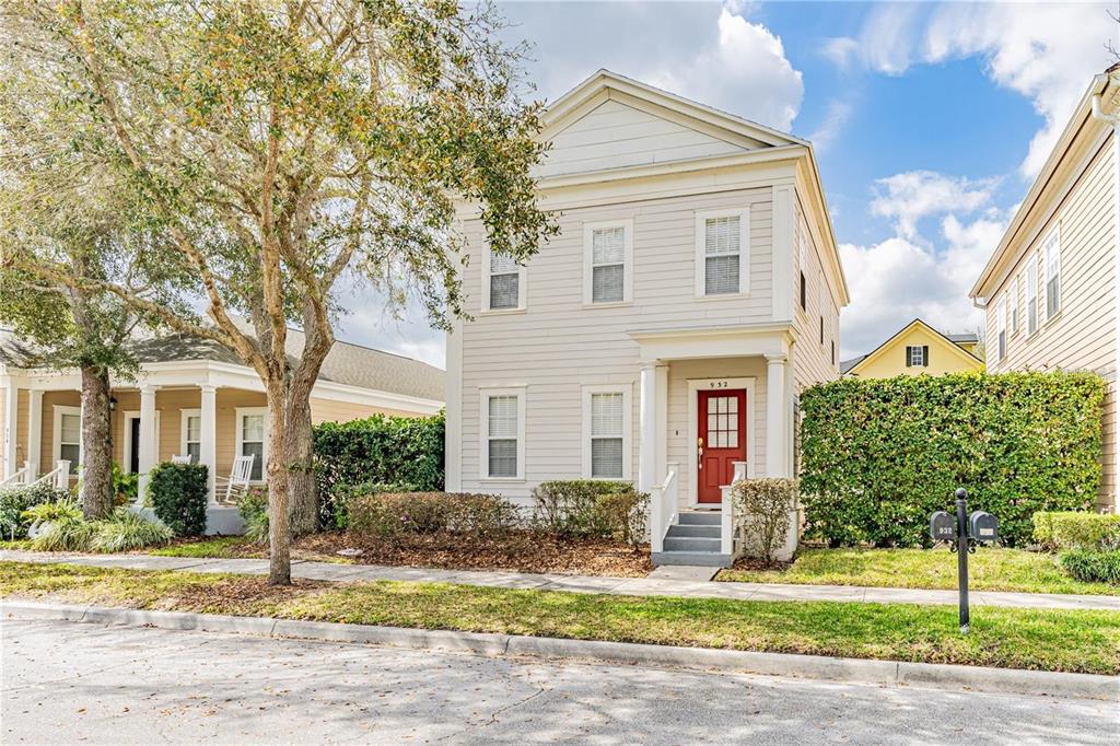 A two-story, light-colored house with a red front door and a large tree nearby — 932 PAWSTAND ROAD, CELEBRATION, FL