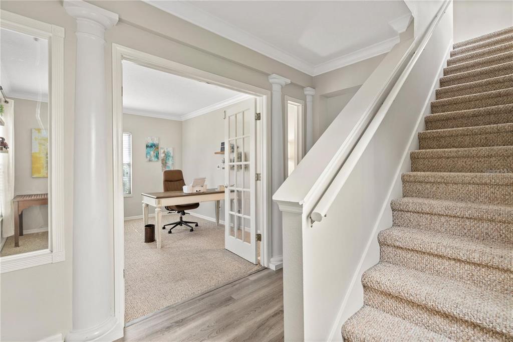A carpeted staircase sits beside a home office with French doors and white columns — 932 PAWSTAND ROAD, CELEBRATION, FL